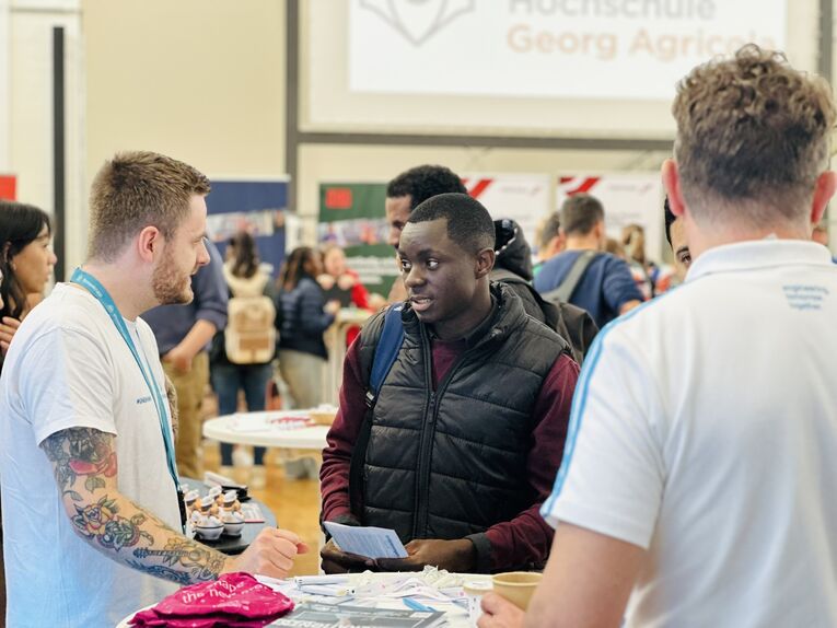 Ein Absolvent im Gespräch mit Firmenvertretern. 