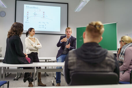 Zu sehen sind Studierende zusammen mit einem Professor in der Diskussion
