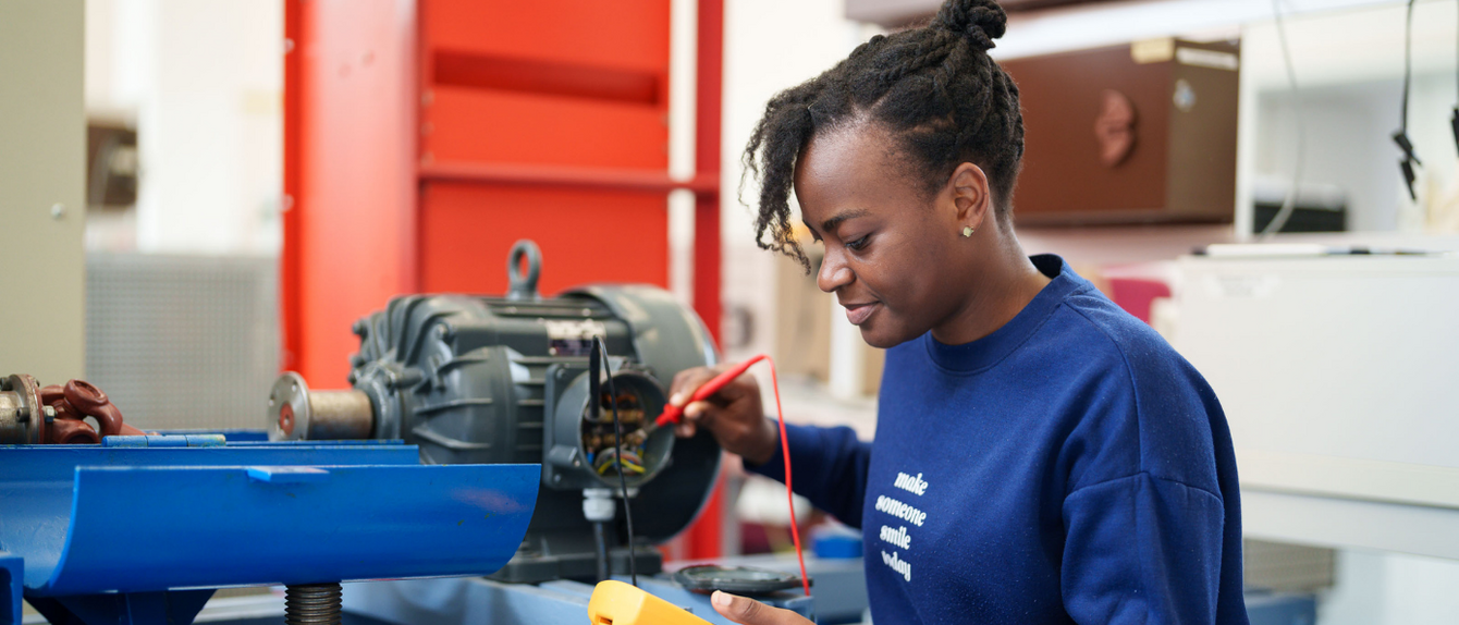 Praxisarbeit im Labor: Studierende prüft mit Messgerät eine Maschine im Labor für Leistungselektronik.