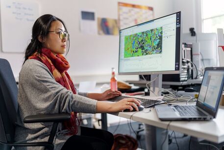 Bergbauingenieurin am Computerarbeitsplatz mit einer grafischen Auswertung auf dem Monitor. 