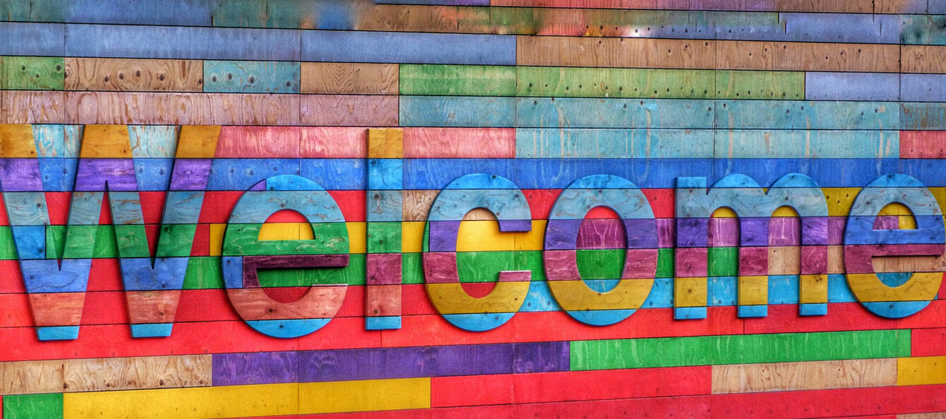 Welcome steht auf einer farbigen Wand.