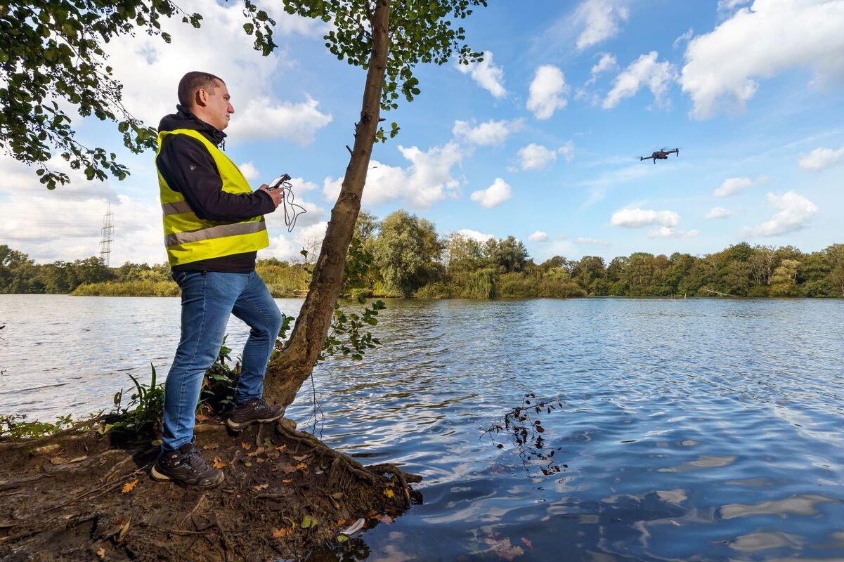 Wissenschaftler steht an einem Bergsenkungssee und überwacht mit einer Drohne die Umwelt. 
