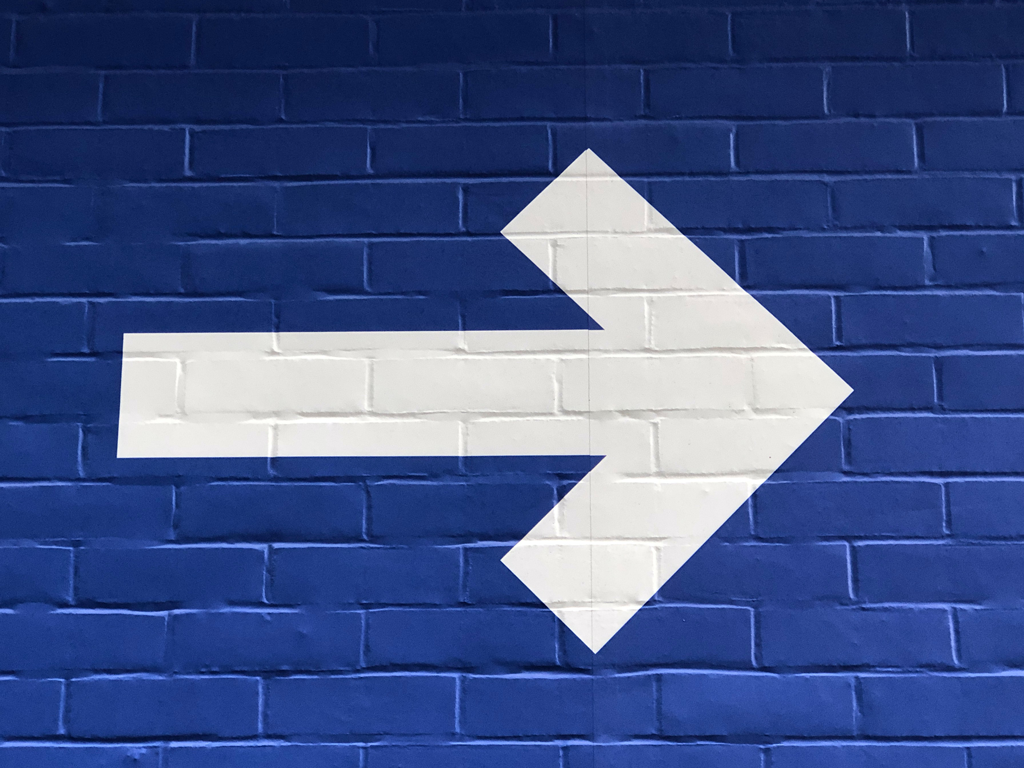 Weißer Pfeil auf blauer Wand