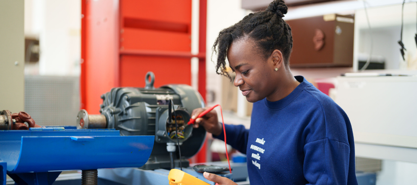 Praxisarbeit im Labor: Studierende prüft mit Messgerät eine Maschine im Labor für Leistungselektronik.