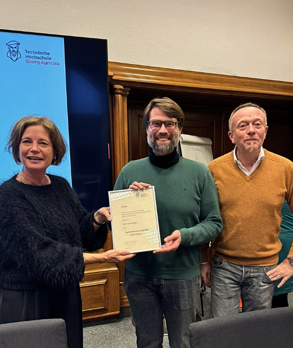 Urkundenüberreichung für den Preis der besten Lehre an der THGA durch Prof. Susanne Lengyel mit Prof. Prange. Ausgezeichnet wird Prof. Robin Wegge